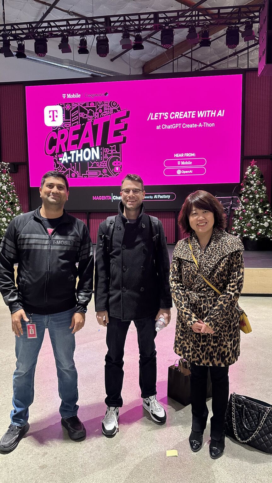Jie with two colleagues in front of the Create-A-Thon stage screen